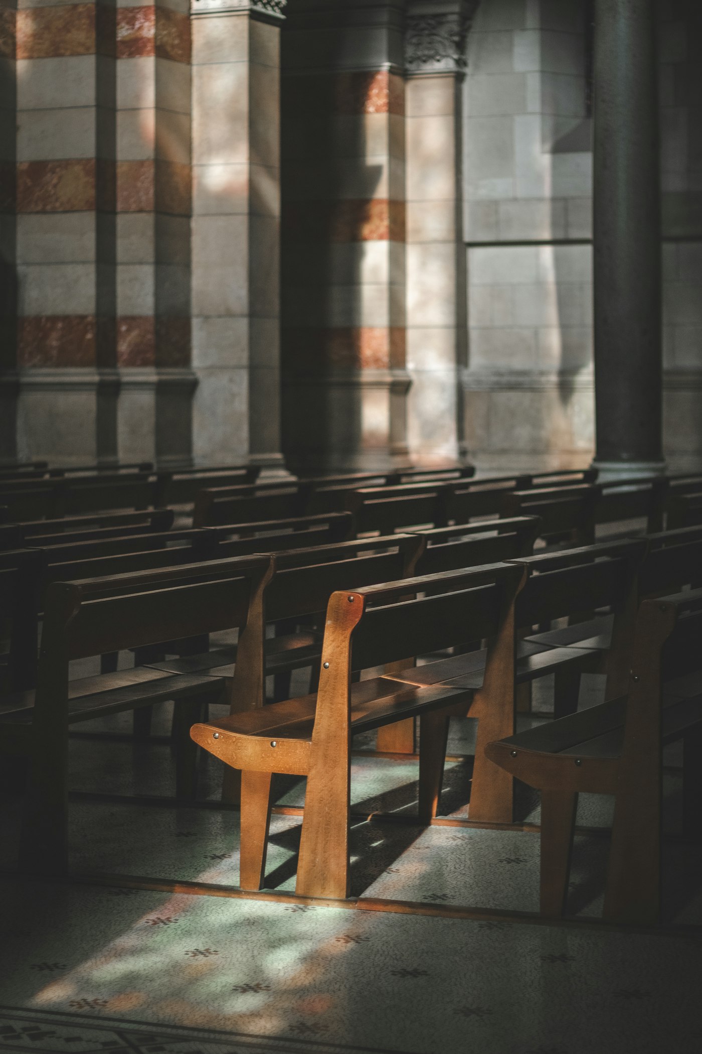 Empty wooden church pew lit by a single window