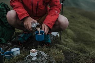 man pouring brown liquid on blue cup