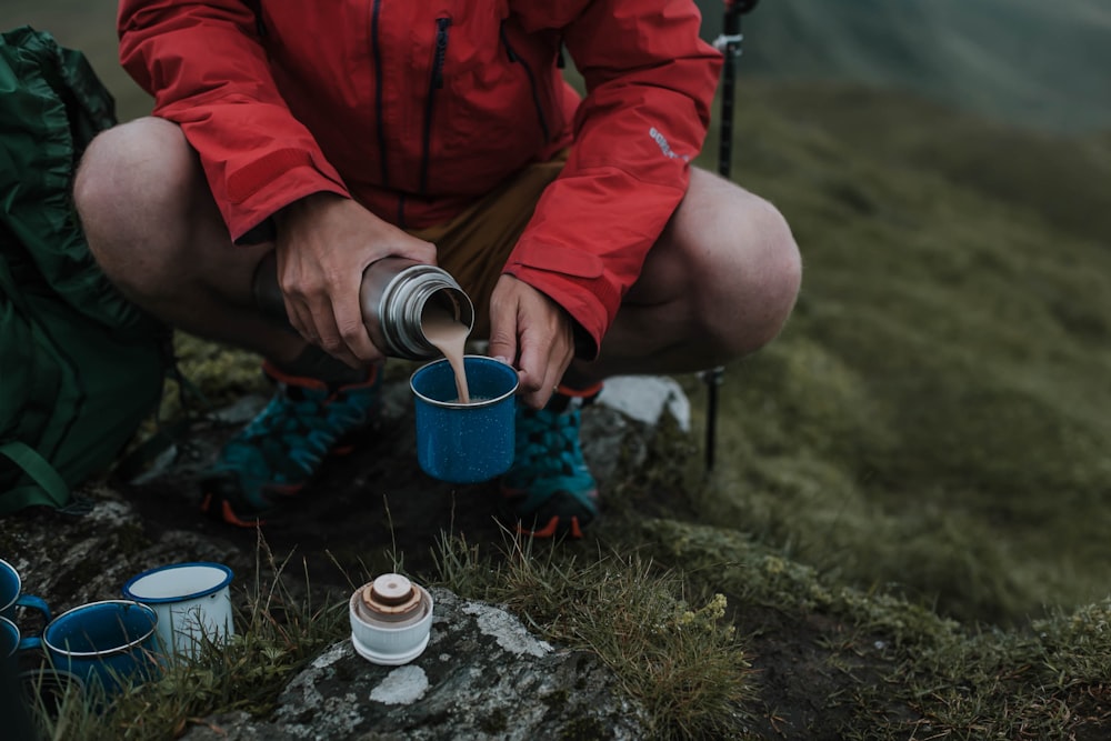 homme versant un liquide brun sur une tasse bleue