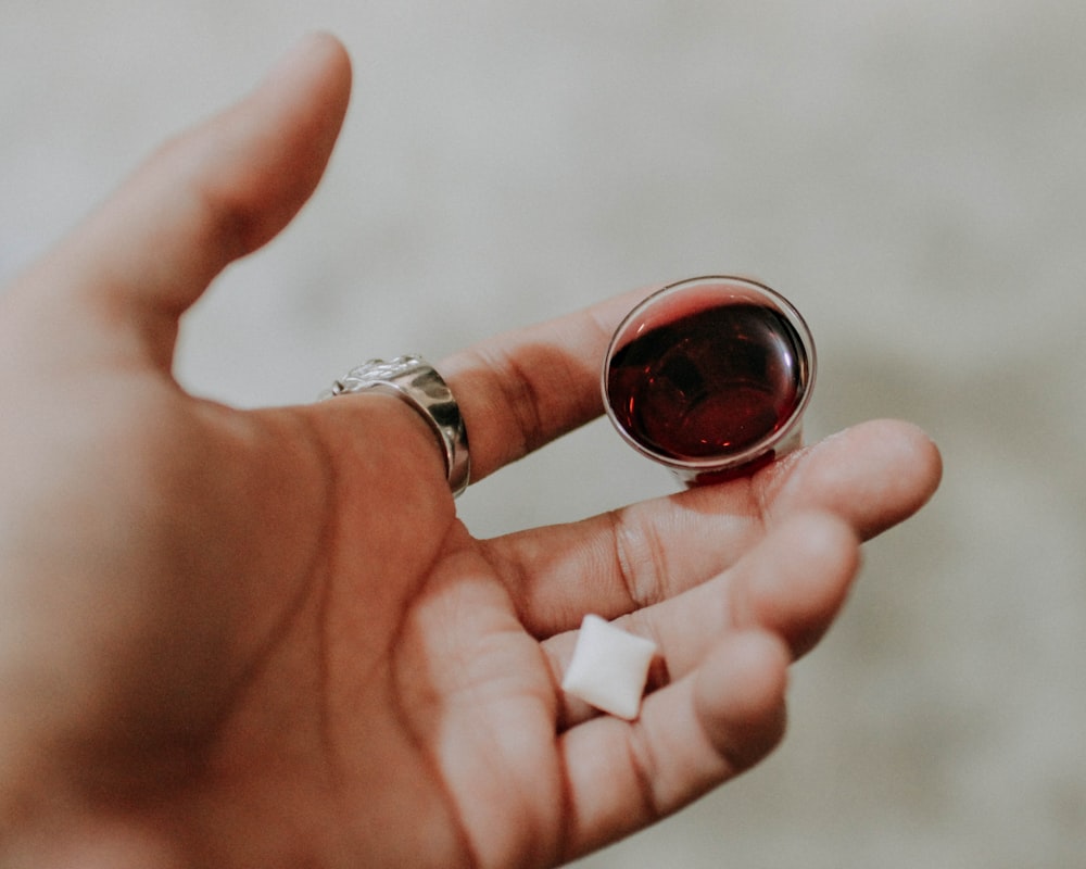 a person holding a small glass of wine in their hand