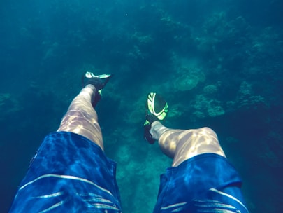 A swimmer wearing a snorkel and fins practicing technique in a clear blue pool.