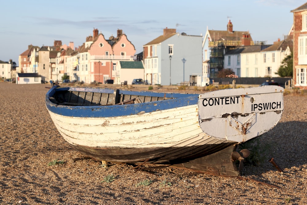 white and blue boat on sea shore