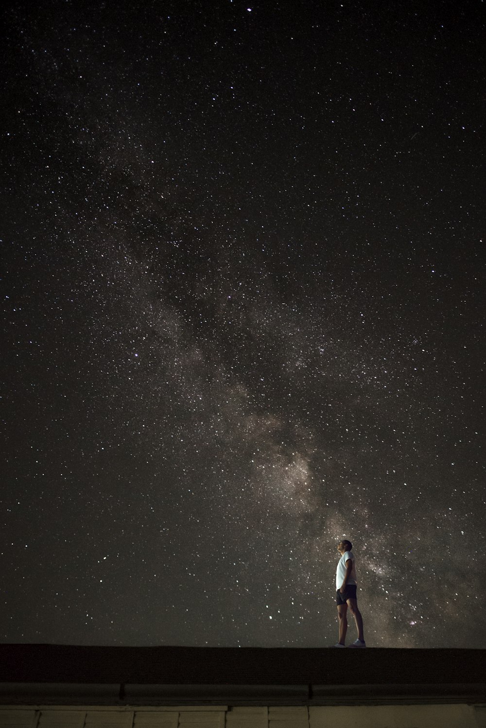 man looking up to Milky Way galaxy at night sky