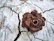 Close-up of a textured ceramic sculpture resting on a warm cream surface with gentle shadows.