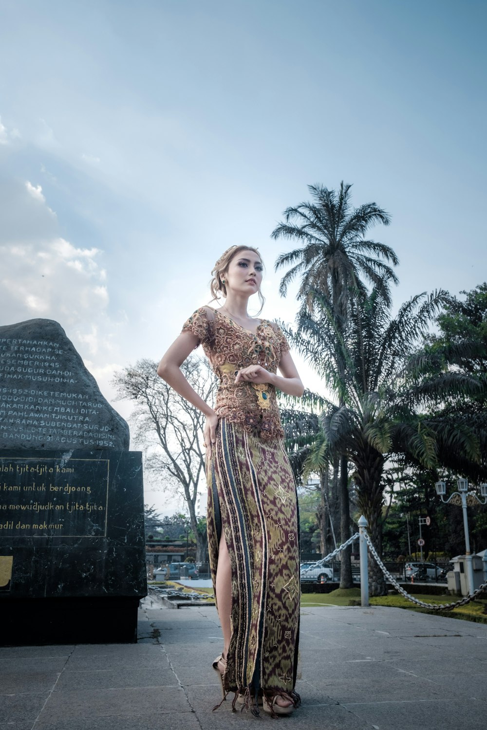 Donna in maxi abito floreale multicolore a maniche corte in piedi davanti alla statua commemorativa