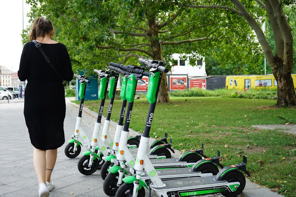 Frau geht neben geparkten Elektrorollern