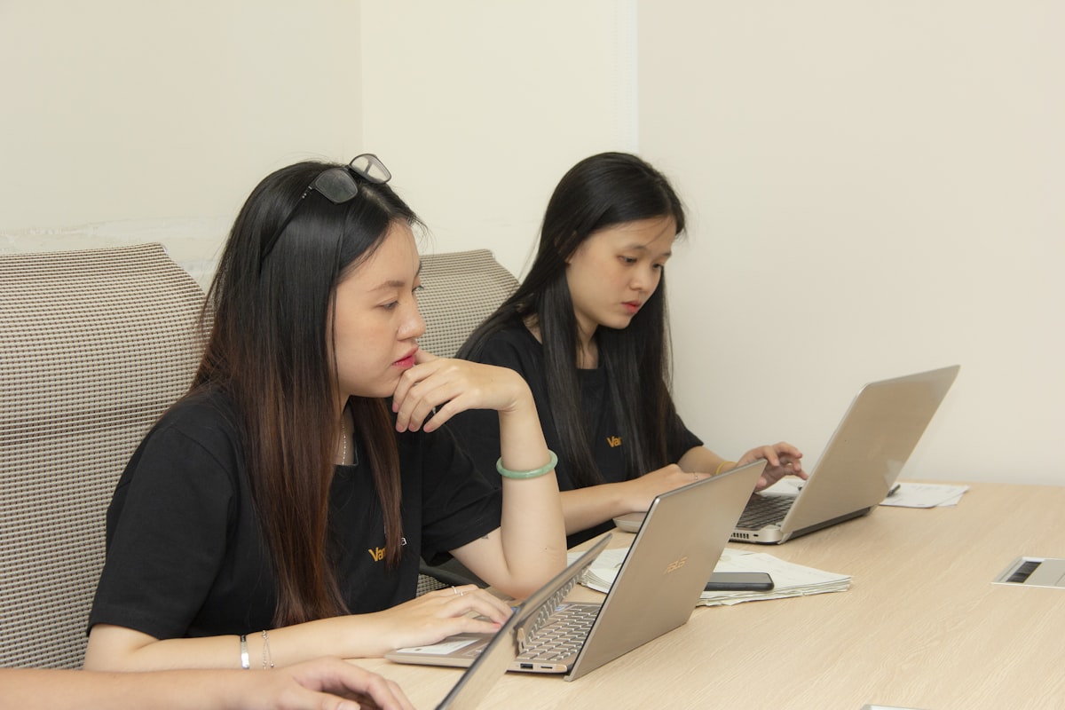 Asian business professionals comparing cross-border e-commerce platform options on laptops for selling in China