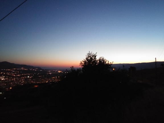 A serene landscape at dusk with glowing city lights.