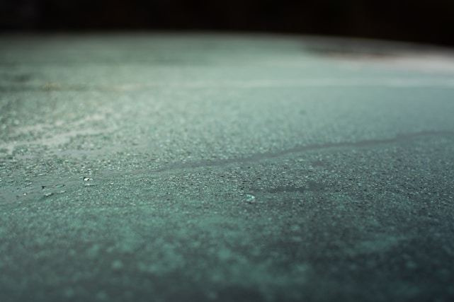 Close-up of a sleek aluminum squeegee with water droplets highlighting its absorption power.