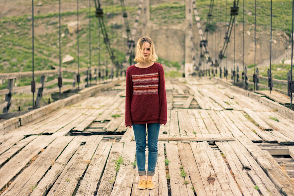 Mulher em pé na ponte suspensa de madeira marrom