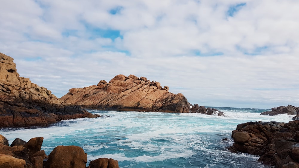 rocks on body of water during cloudy daytime