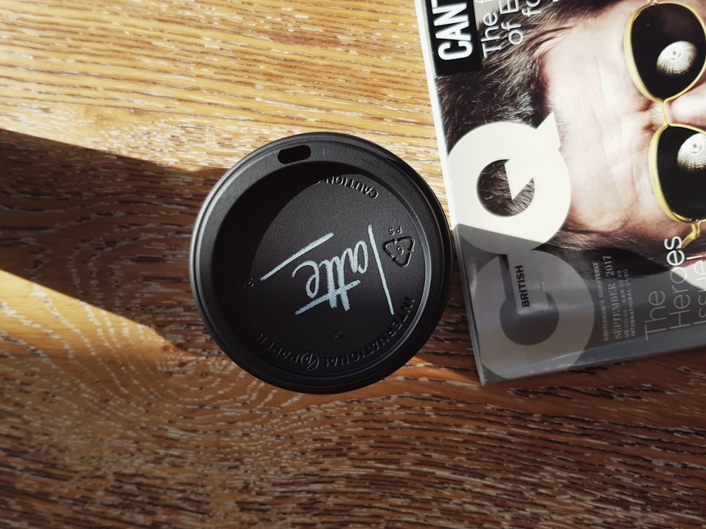black disposable coffee cup besides GQ magazine
