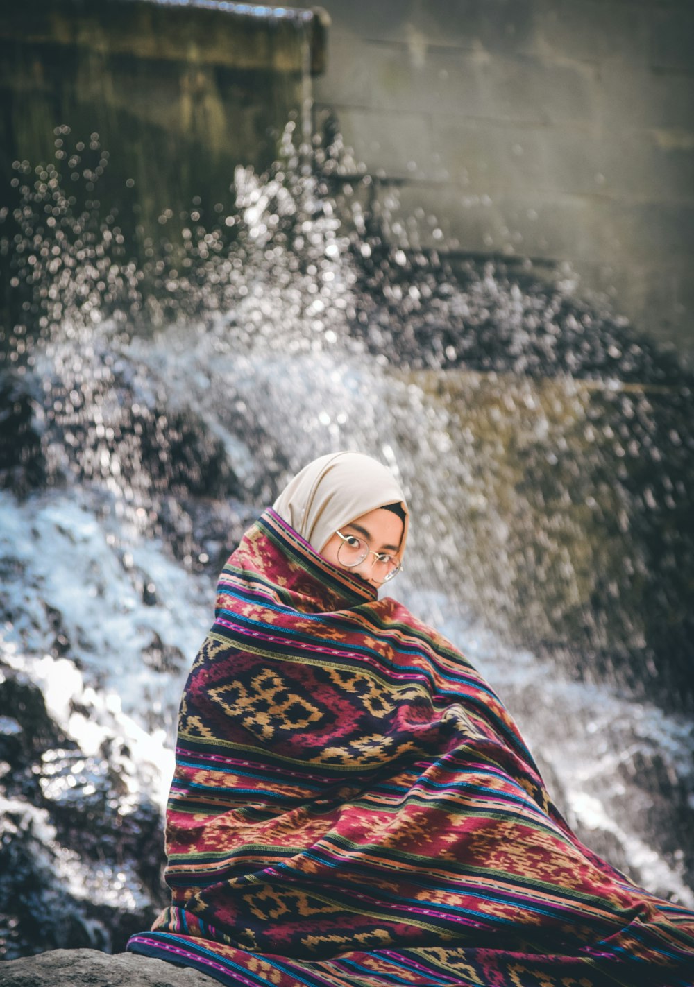 woman sitting on rock near flowing body of water