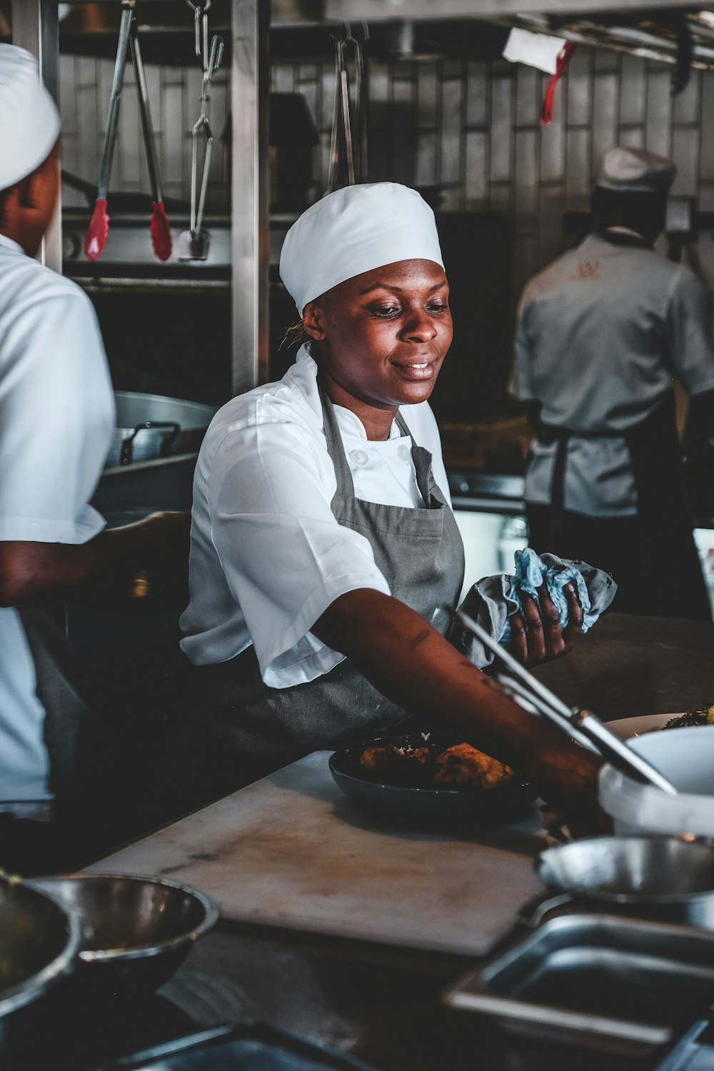 person in white top with gray apron holding pot