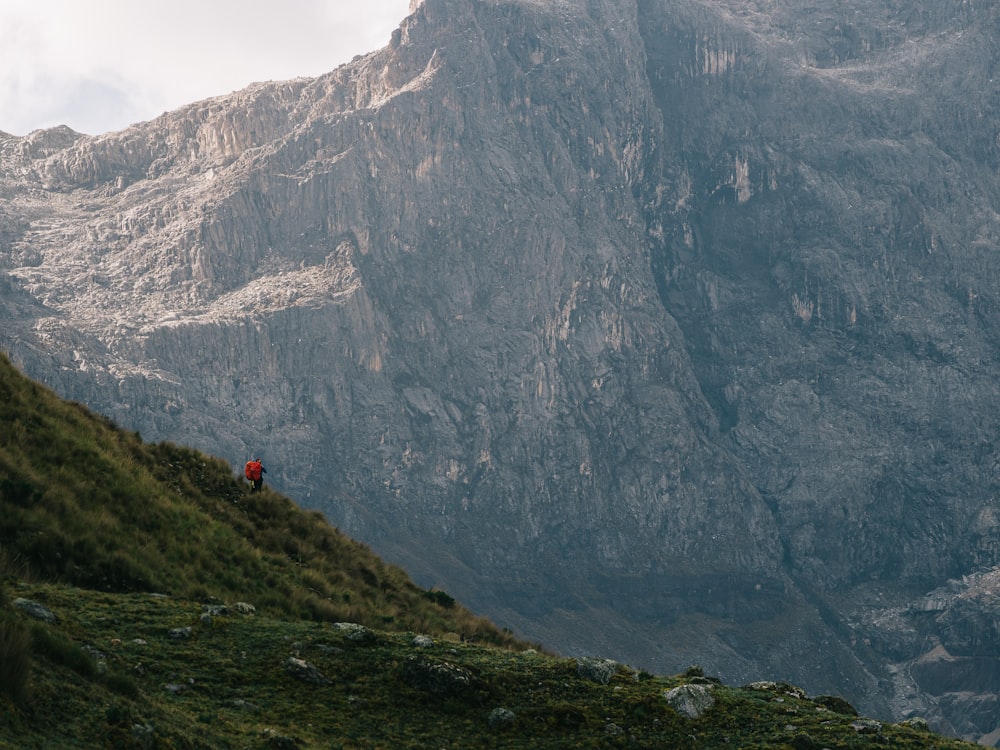 a person walking up a hill with a mountain in the background