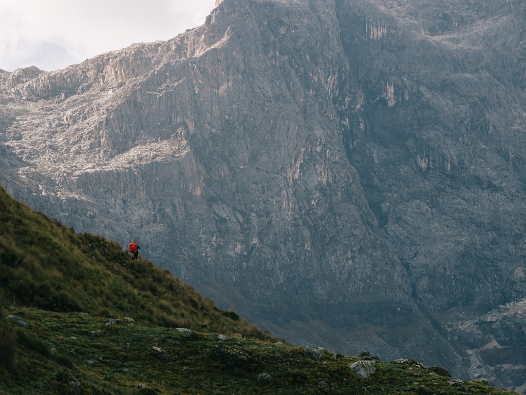 a person walking up a hill with a mountain in the background,
