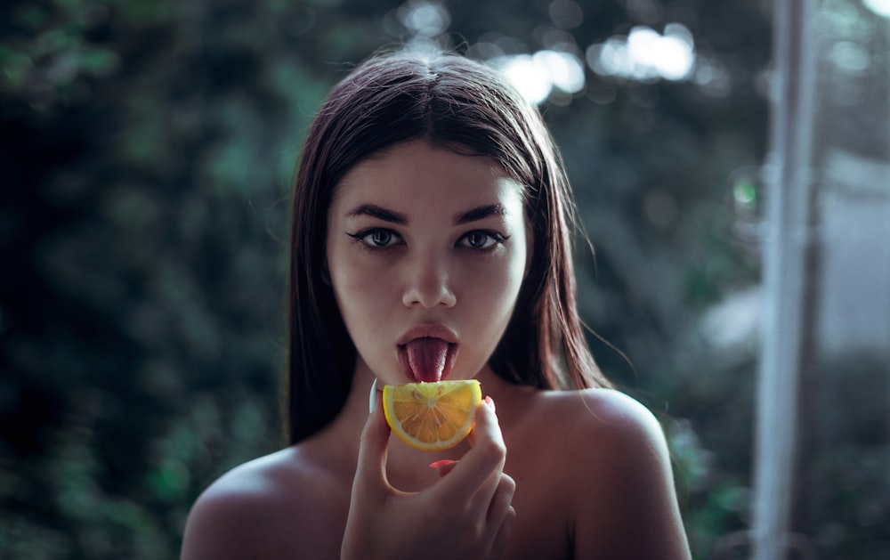 Collect. woman licking slice of orange fruit. 