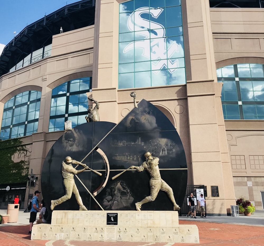 estátua cinzenta do beisebol perto do edifício de concreto