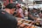A man enjoying sushi at a bustling Tokyo street market at night.