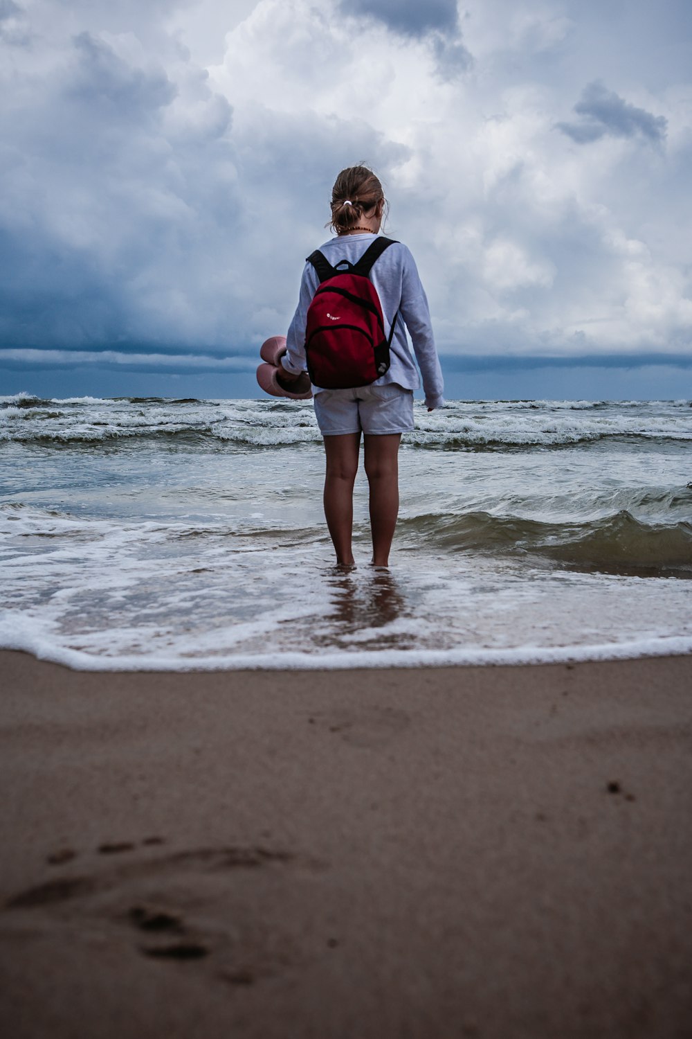 woman in gray jacket standing on seashore