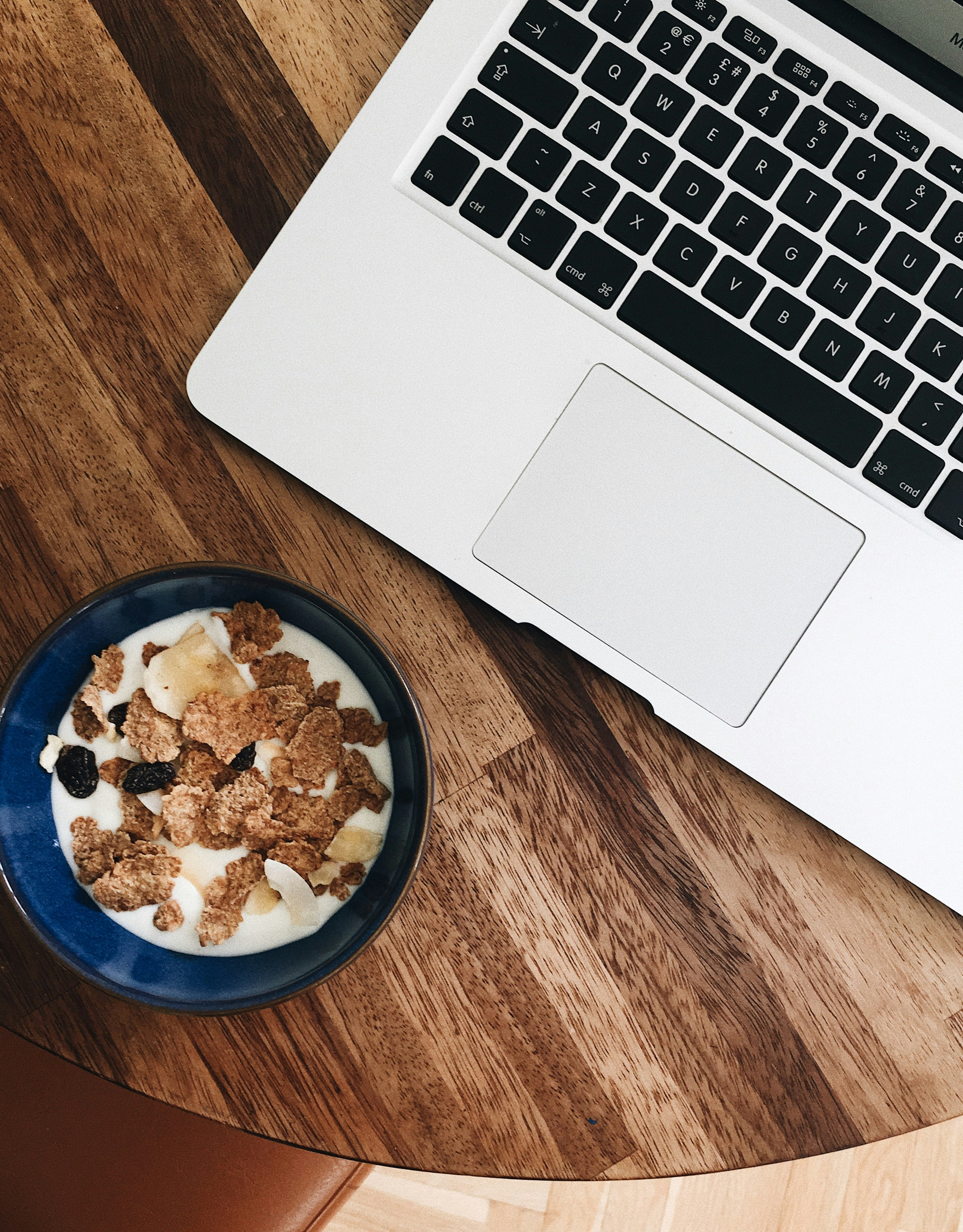 sereal dengan susu dalam mangkuk di dekat MacBook Pro