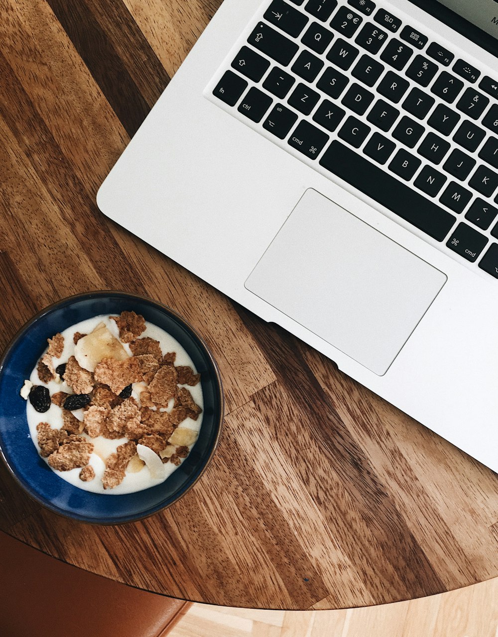 cereal with milk in bowl near MacBook Pro
