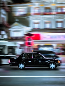 A sleek black taxi waiting outside a cozy Coventry neighborhood at dusk.