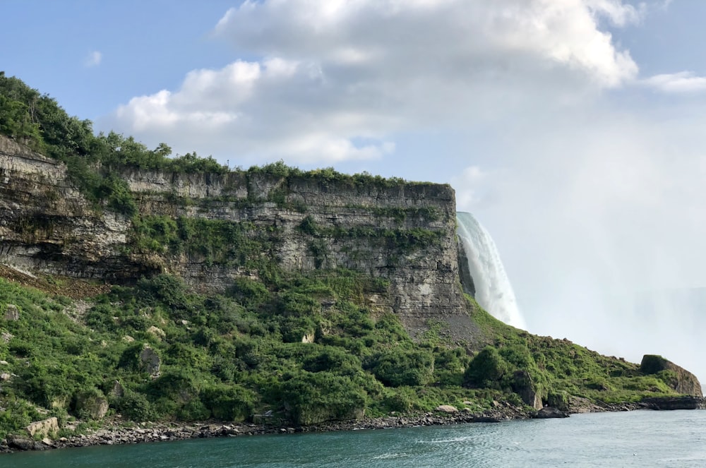 green and grey cliff near body of water during daytime