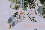 A blend of natural elements with industrial structures creates a surreal, urban jungle-like scene. The overlapping composition includes branches and leaves in front of a gym playground with equipment visible, suggesting an interplay between nature and modernity.