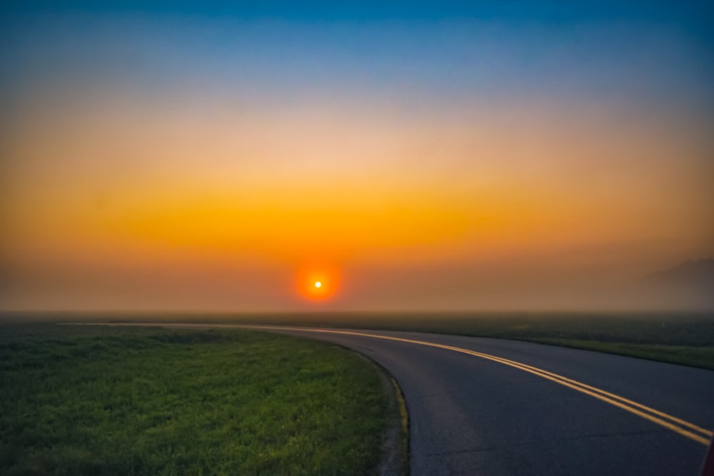 curved paved road during golden hour