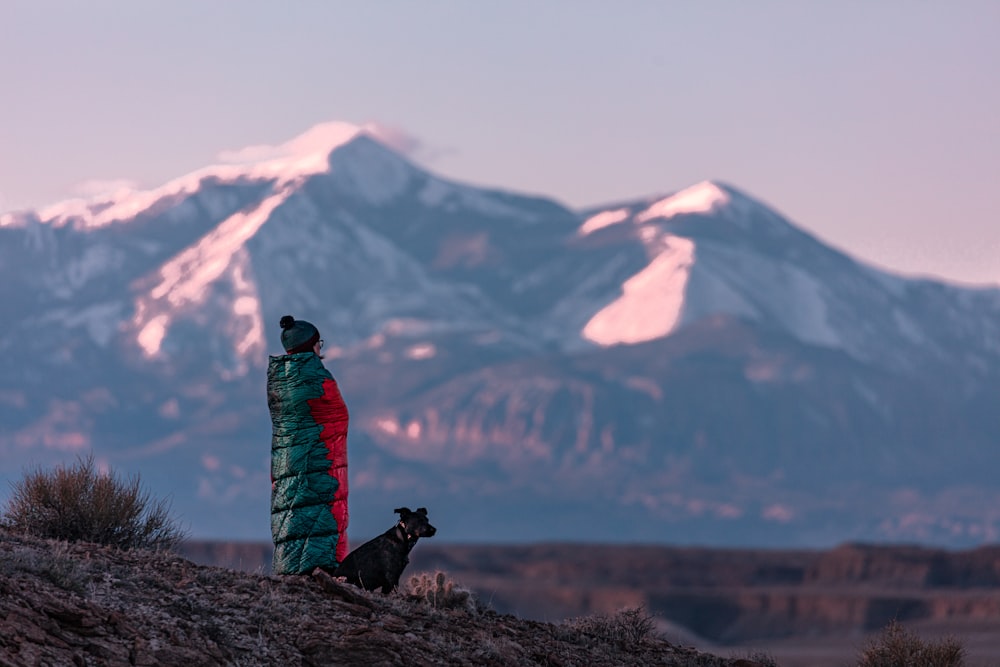 man and dog standing near black and white mountain view