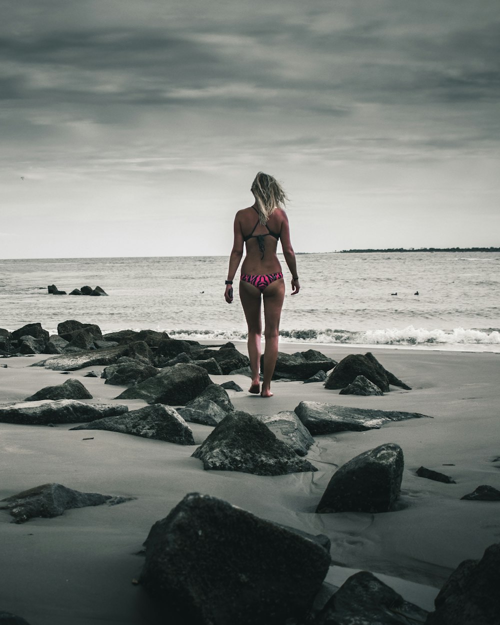 woman in pink bikini standing in rocky beach