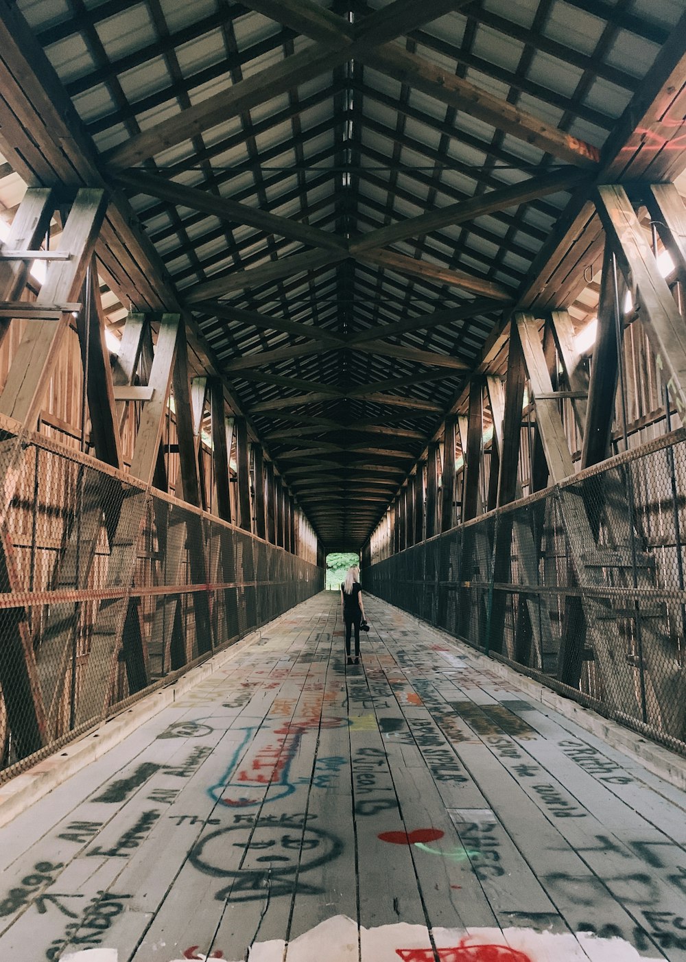 a person standing on a wooden walkway with graffiti on it