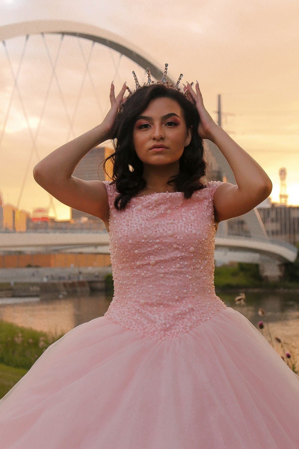 woman wearing pink sleeveless dress standing and touching her crown