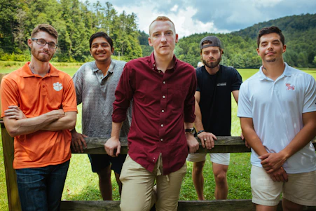 five men standing by a wooden fence