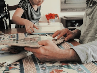 A family gathered around a coffee table, reading a memory book together.