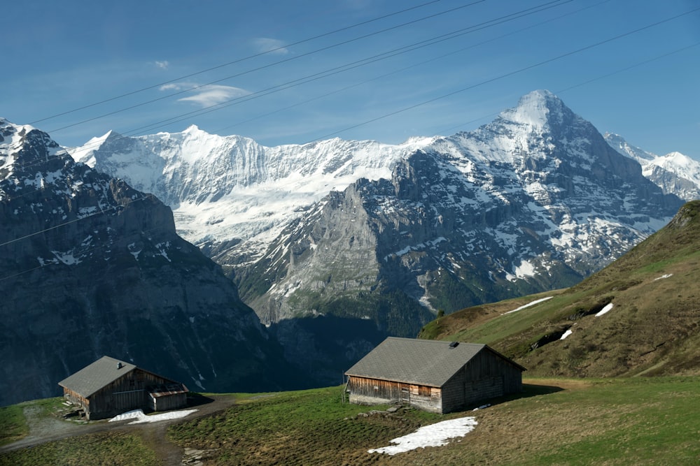 two gray roofed houses on green hill farm from rocky mountain ranges