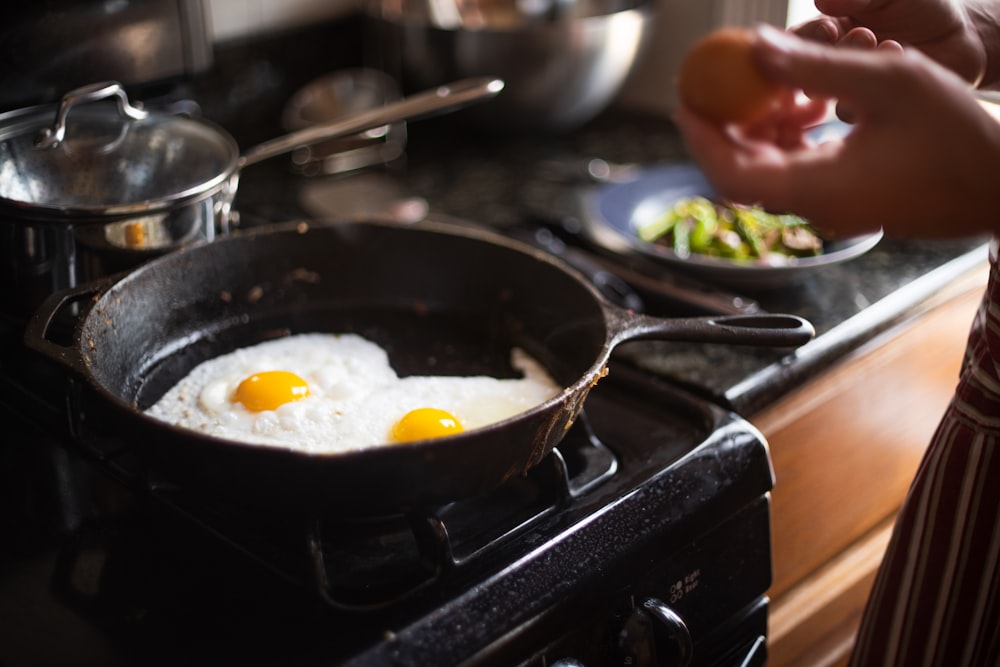 Photographie culinaire de deux œufs au plat sur une poêle en fonte