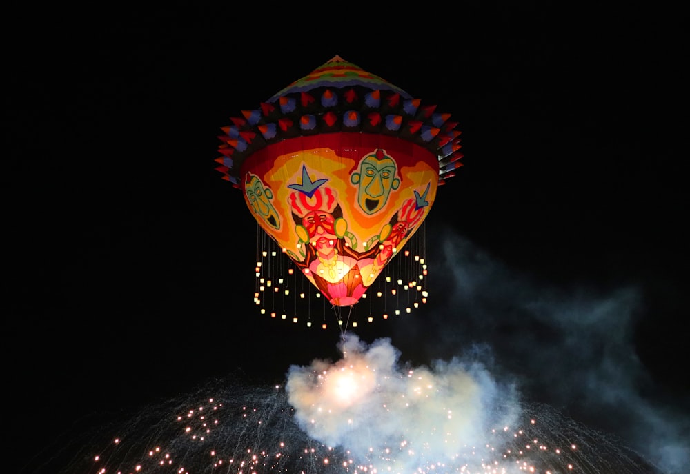 a large colorful lit up balloon floating in the air