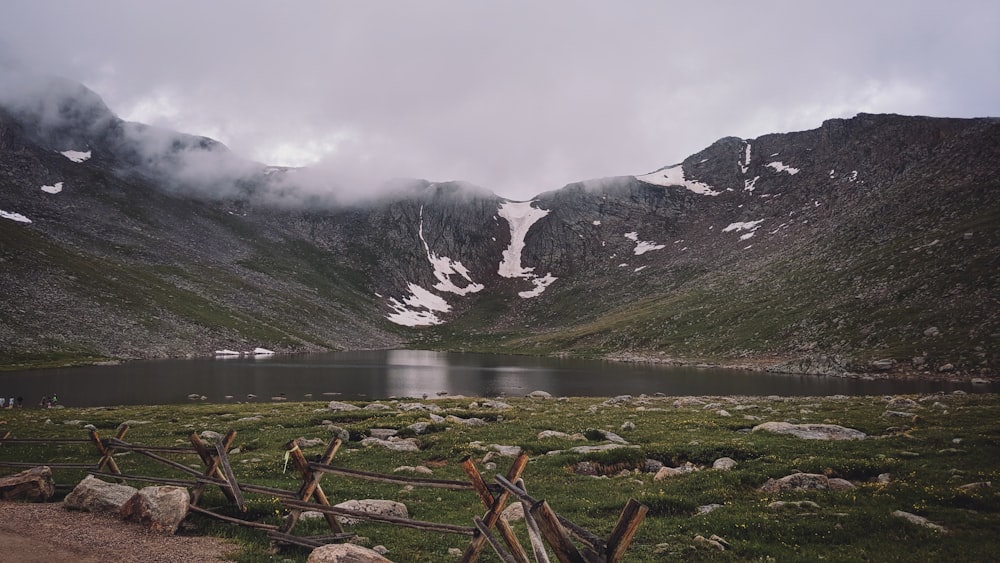 lake, mountains, and grass land during day