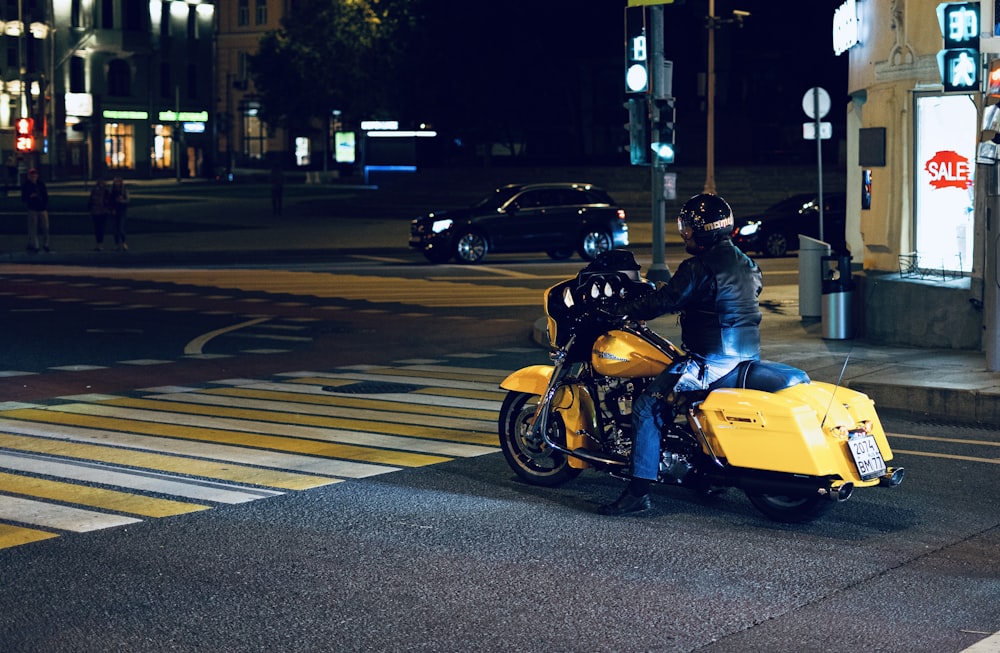 Ein Mann, der mit einem gelben Motorrad eine Straße entlang fährt