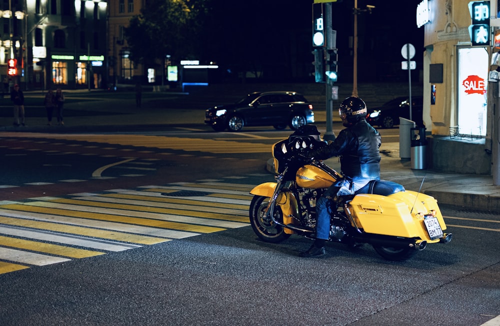 a man riding a yellow motorcycle down a street