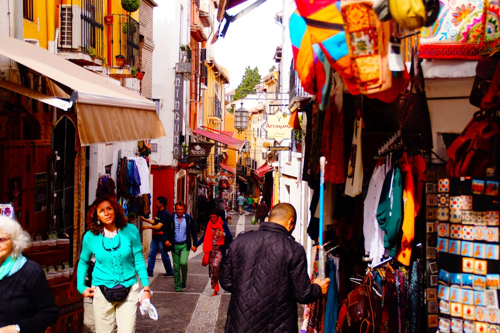 a group of people walking down a street next to shops