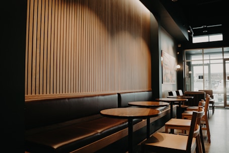 round brown wooden tables beside black leather sofa