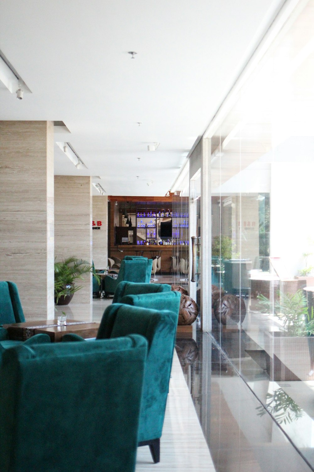 teal suede sofa beside glass wall