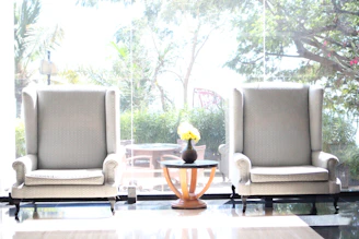 A set of elegant wooden chairs arranged around a small coffee table with decorative plants.