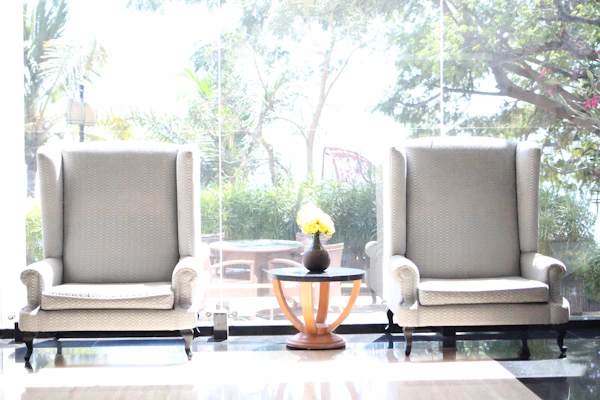 A set of elegant wooden chairs arranged around a small coffee table with decorative plants.