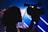 A silhouetted figure, possibly a child, is operating a video camera with a bright, colorful background illuminated by blurred lighting lines.