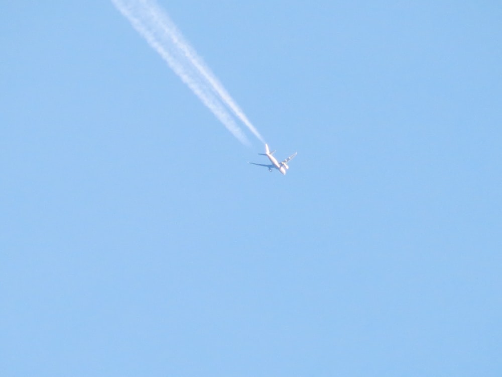 Un avión volando en el cielo con una estela detrás