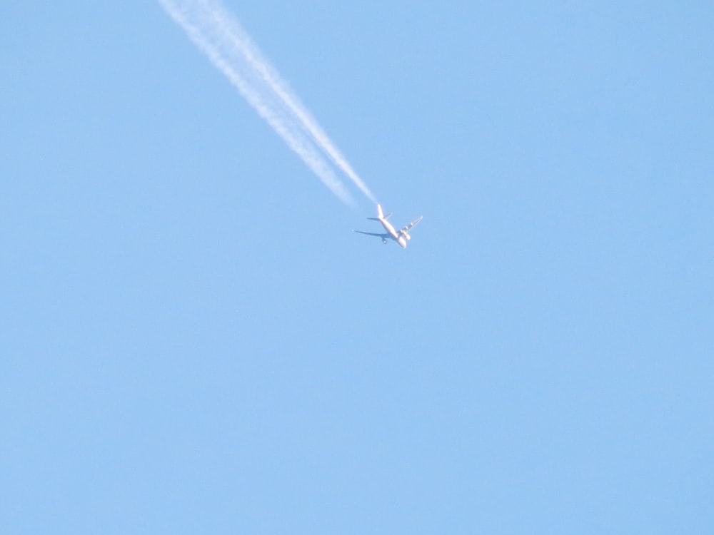 un avion volant dans le ciel avec une traînée de condensation derrière lui